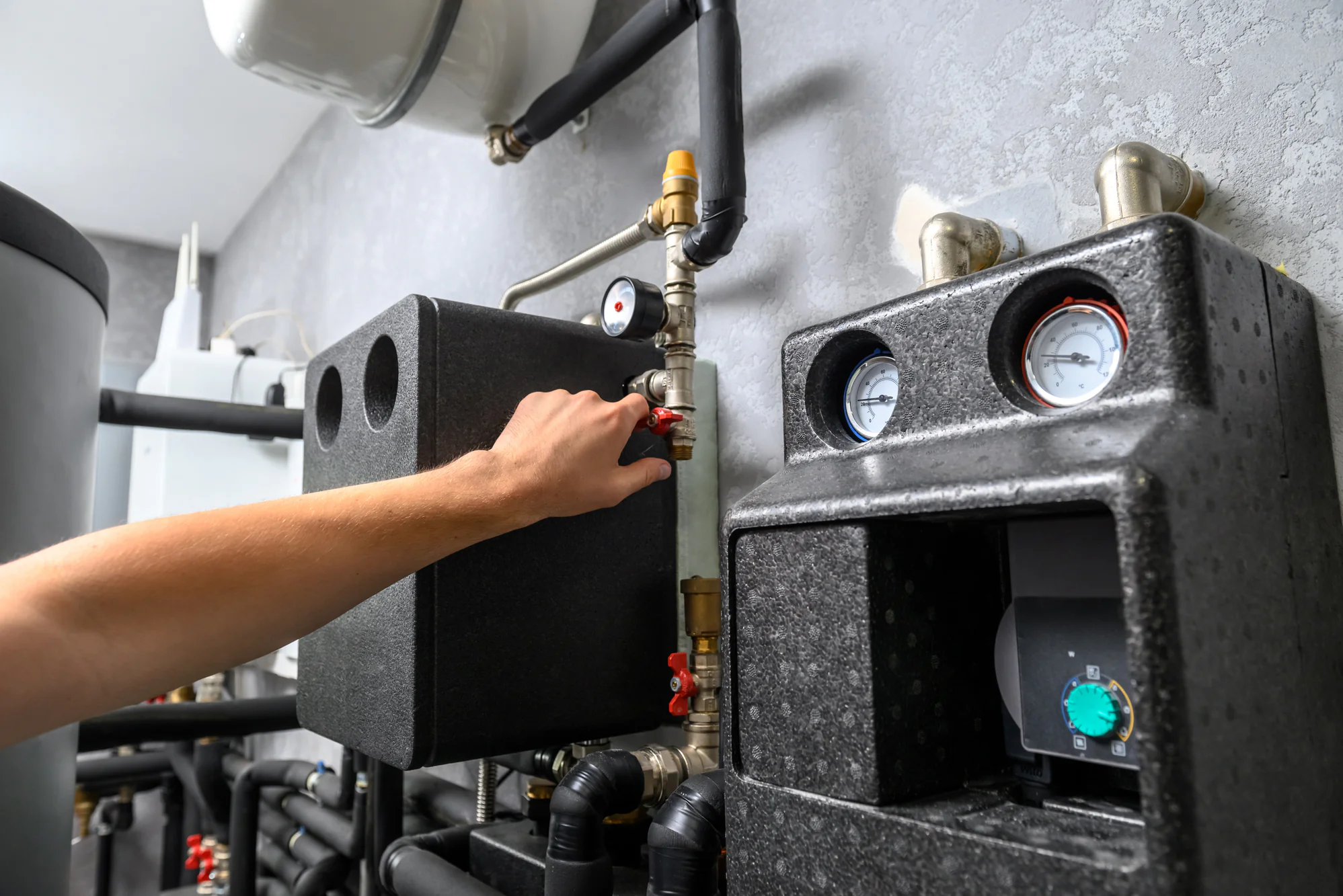 A person adjusts a valve on an HVAC system, commonly seen during AC installation in Essex County, NJ.
